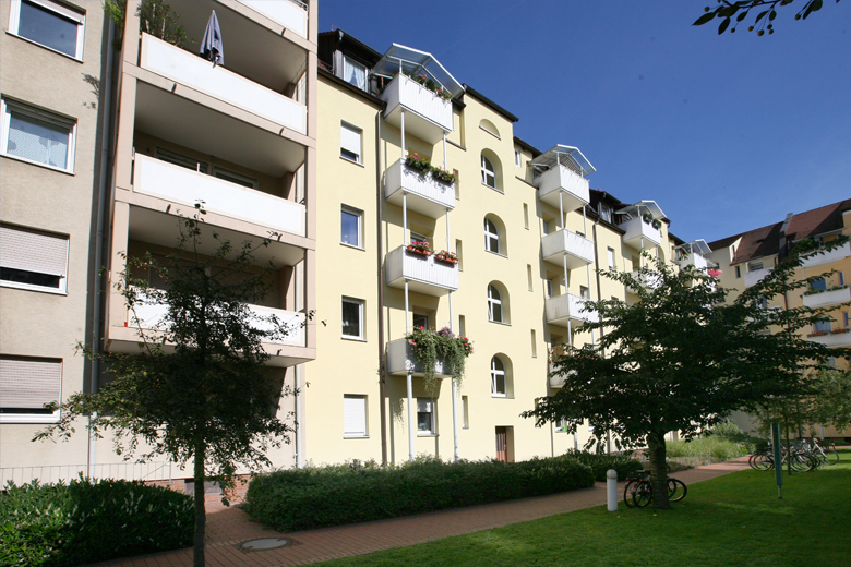 Mehrfamilienhaus in der Bertastraße 10 in Nürnberg mit runden Balkonen, Vorgarten mit Bäumen und Fahrradstellplatz