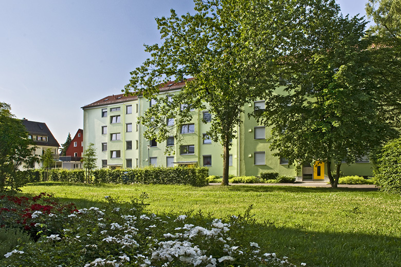 Mehrfamilienhaus in der Goldweiherstraße 43-47 in Nürnberg, Frontansicht mit gelber Fassade, Rasenfläche und Blumenbeeten