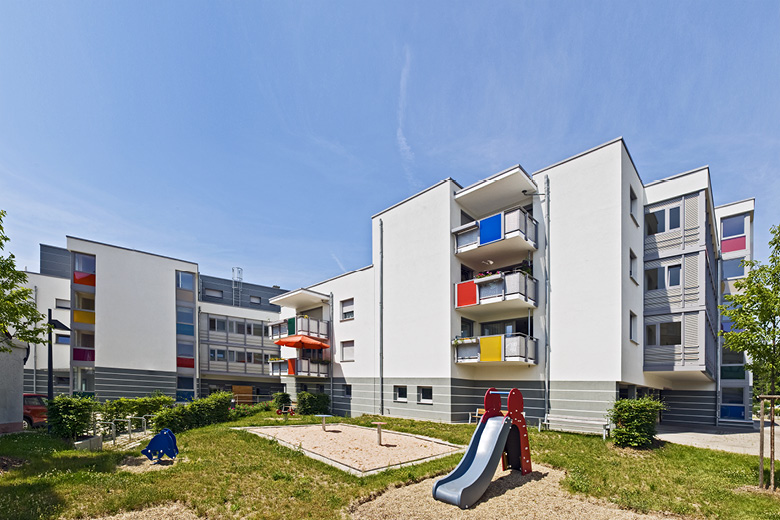 Mehrfamilienhaus in der Kachletstraße 8 in Nürnberg, Rückansicht mit bunten Balkonen und Spielplatz mit Rutsche