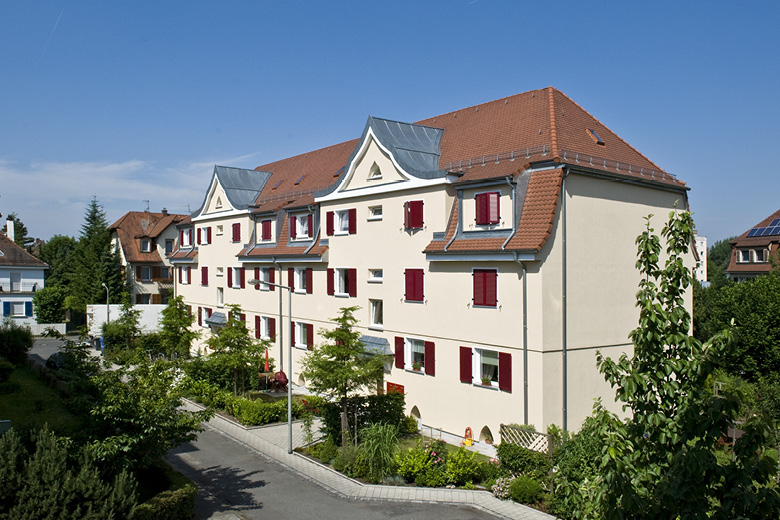 Wohnhauszeile in der Rohrmattenstraße 5-7 in Nürnberg, Frontansicht mit Giebeln, roten Fensterläden und Vorgarten