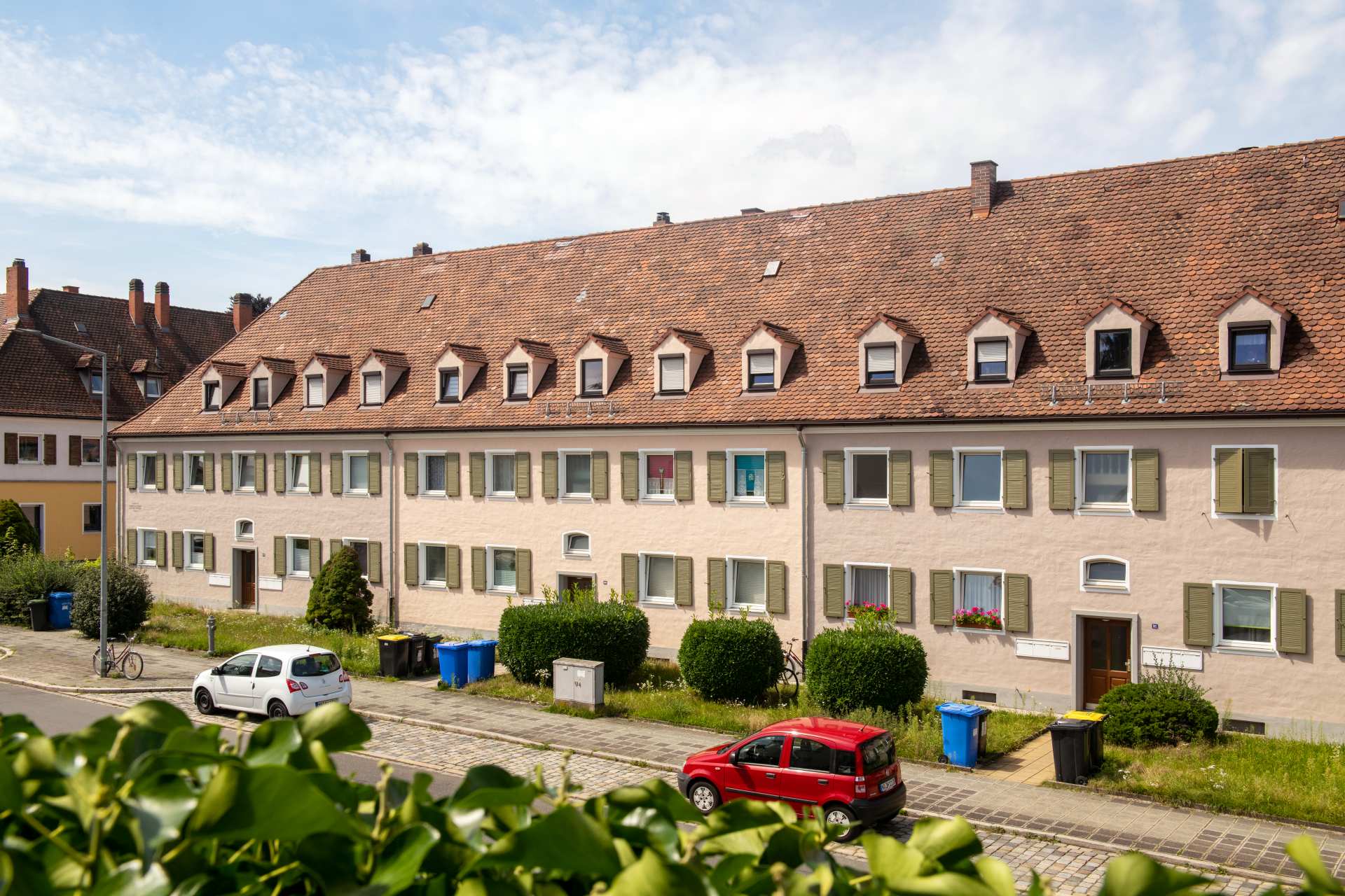 Reihenhauszeile Waldluststraße in Nürnberg mit Sprossenfenstern, Dachgauben und Ziegeldach, davor parkende Autos und Mülltonnen