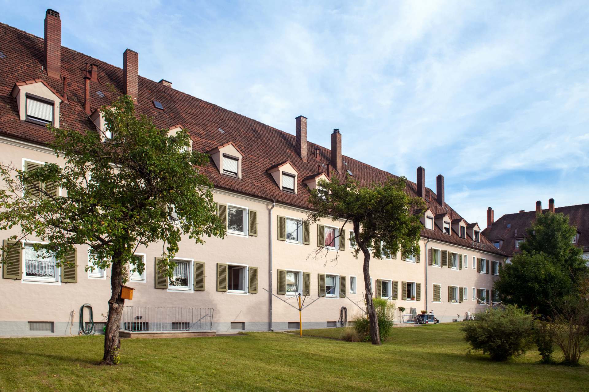 Reihenhauszeile in der Waldluststraße in Nürnberg mit Gauben und Kaminen, Blick über den grünen Garten mit Bäumen
