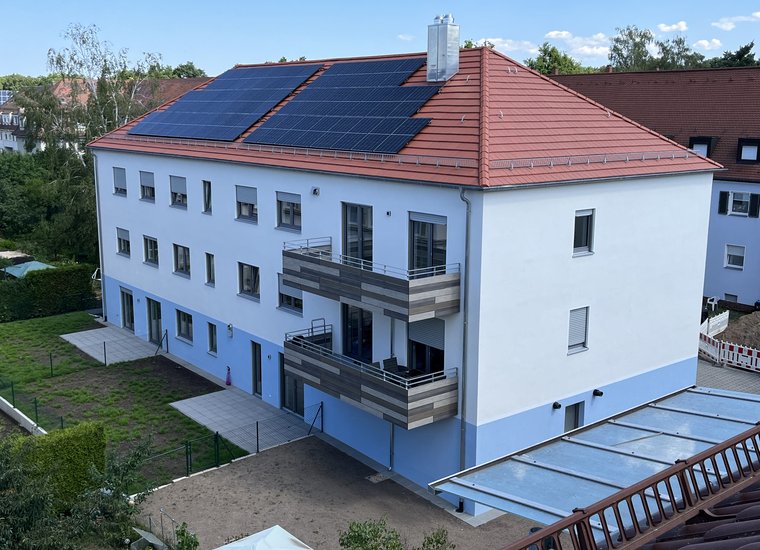 Neu gebautes Mehrfamilienhaus mit Solaranlage auf dem Dach in der Geuschmidstraße 11, Luftaufnahme der Rückseite mit Balkonen und Garten